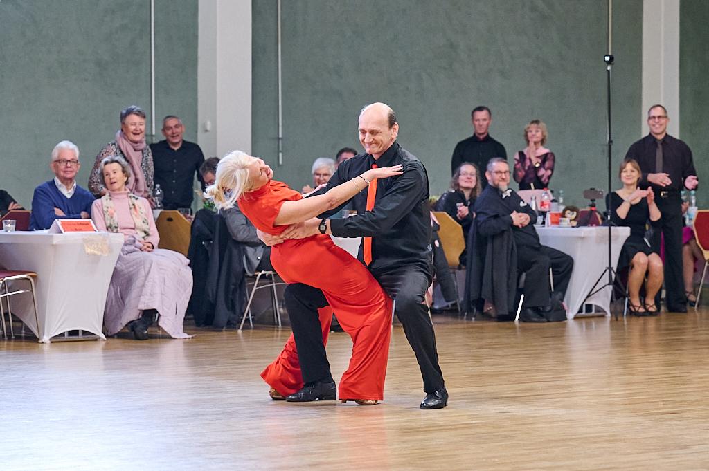 Tanzpaar f&uuml;hrt einen leidenschaftlichen Tanz auf einer Veranstaltung, umgeben von applaudierendem Publikum.