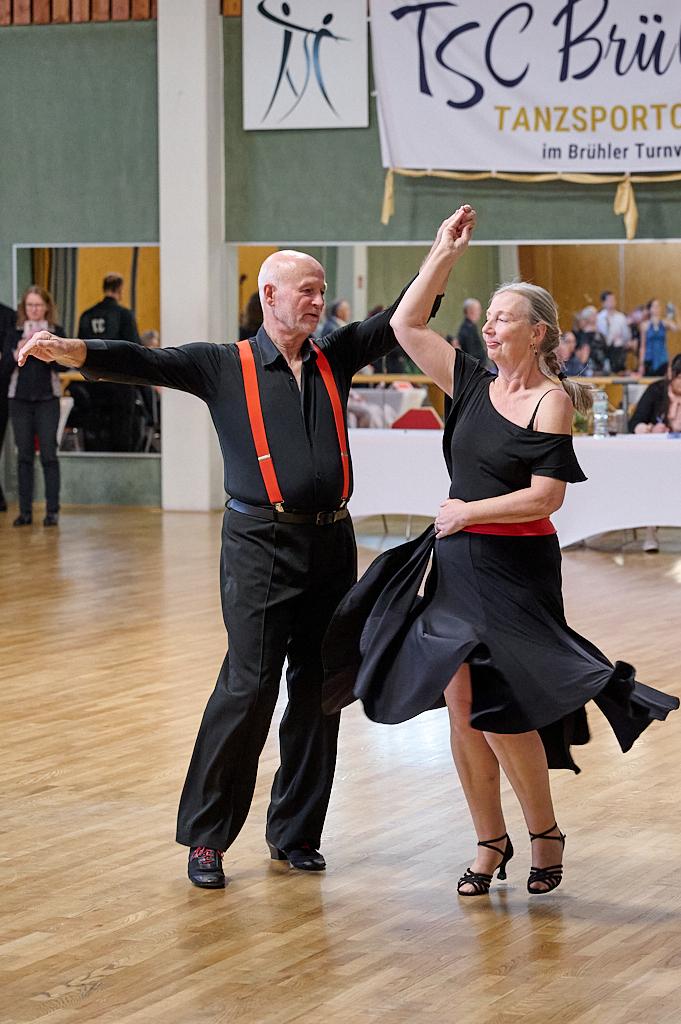 Tanzendes Paar in eleganter Kleidung, der Mann mit roten Hosentr&auml;gern und die Frau in einem schwarzen Kleid, auf einer Tanzfl&auml;che.