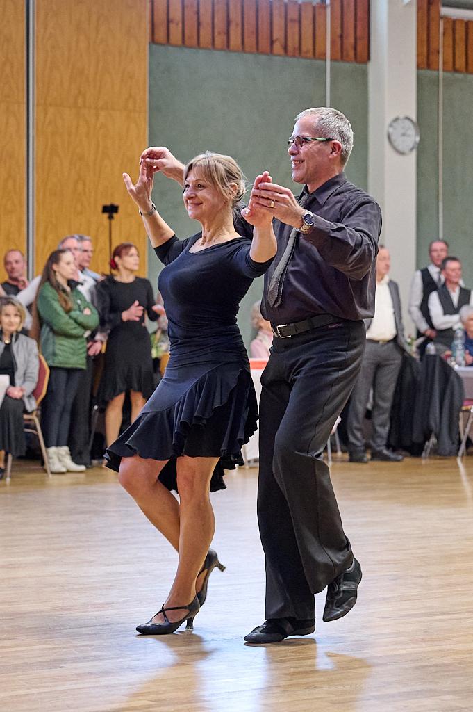 Tanzpaar f&uuml;hrt einen Paso Doble auf einer Tanzfl&auml;che, umgeben von Zuschauern in festlicher Kleidung.