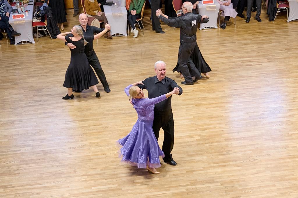 Tanzpaar f&uuml;hrt einen Walzer in eleganter Kleidung auf einem Holzparkettboden bei einer Tanzveranstaltung aus.