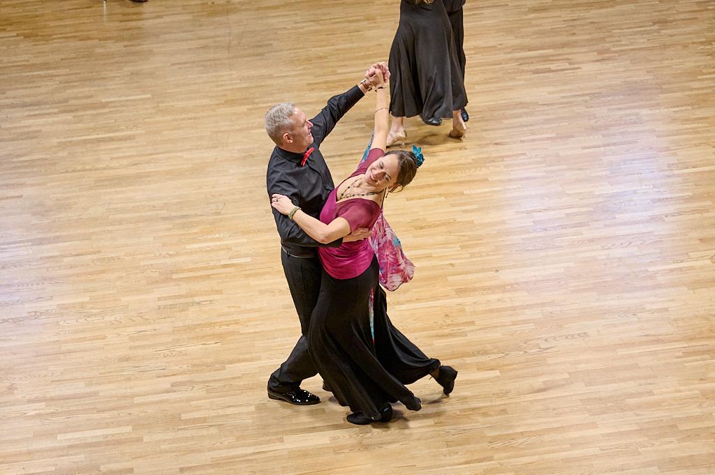 Tanzpaar in eleganter Abendgarderobe tanzt auf einem Holzparkett w&auml;hrend einer Veranstaltung in festlicher Atmosph&auml;re.