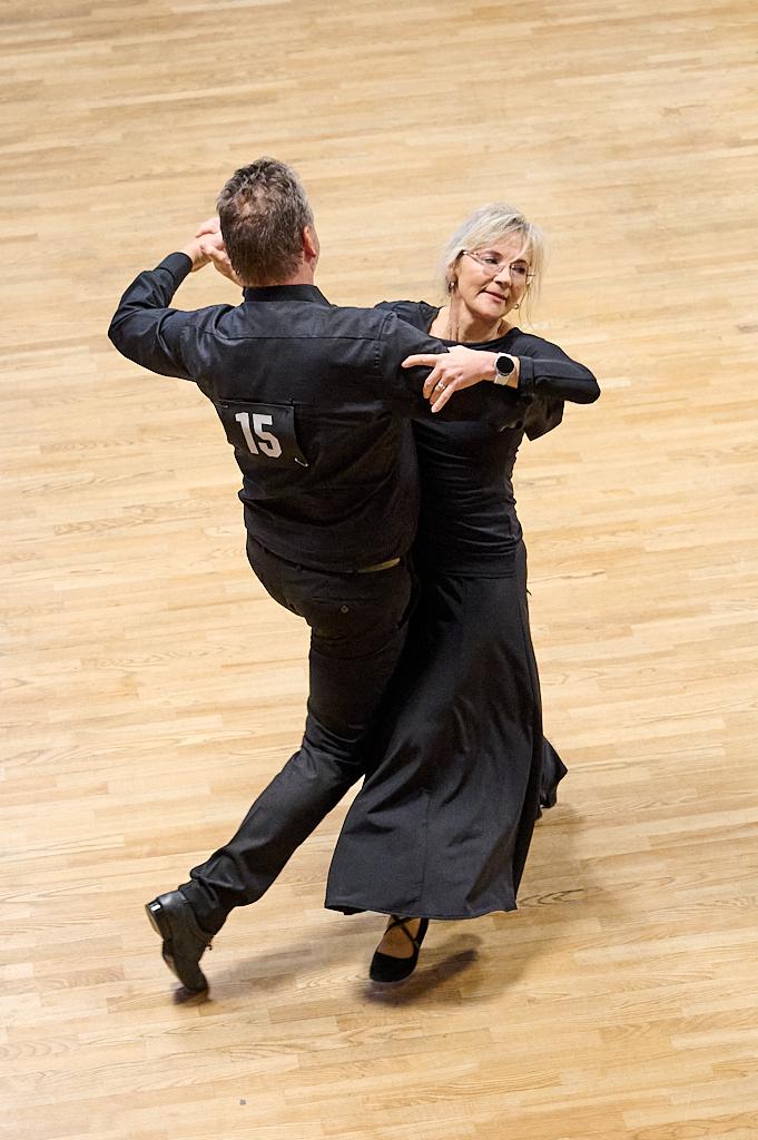 Tanzpaar in eleganter Kleidung f&uuml;hrt einen Tanz auf einem Holzfu&szlig;boden, der M&auml;nner tr&auml;gt eine Nummer 15.