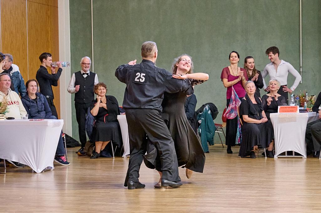 Tanzpaar in eleganter Kleidung tanzt auf einer Veranstaltung, umgeben von applaudierendem Publikum.
