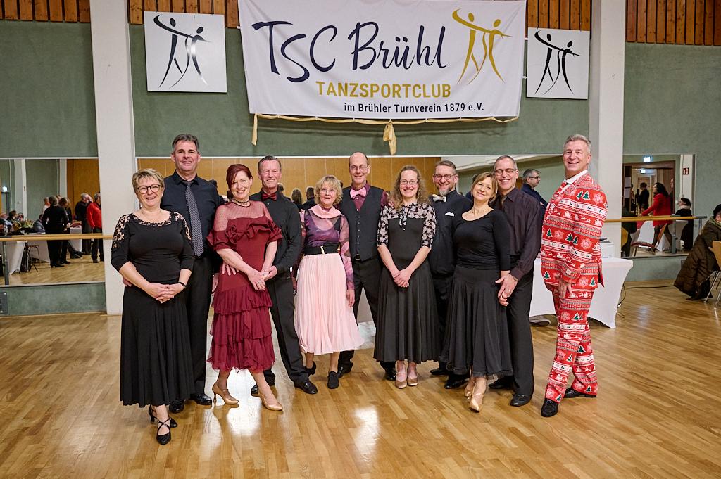 Gruppierung von T&auml;nzern in eleganter Abendkleidung vor Banner des TSC Br&uuml;hl im Tanzsportclub.
