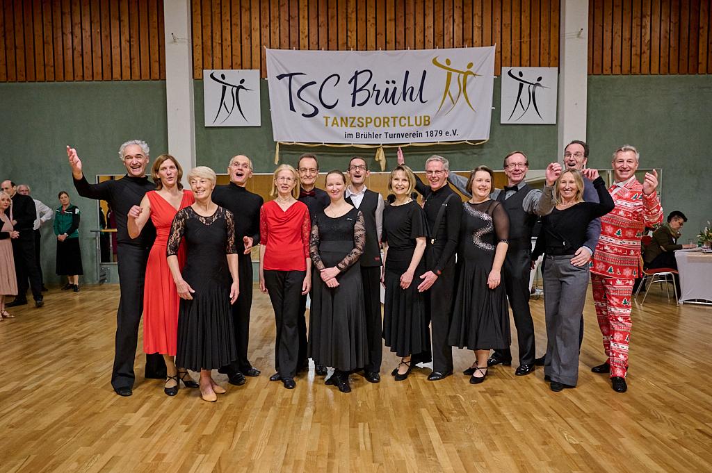 Gruppenfoto von T&auml;nzern in eleganter Kleidung vor einem Banner des TSC Br&uuml;hl im Tanzsportclub.