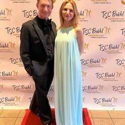 Paar in festlicher Kleidung steht vor einem Banner zum 50-jährigen Jubiläum des TSC Brühl.