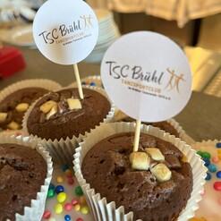 Schokoladenmuffins mit Dekoration und kleinen F&auml;hnchen des TSC Br&uuml;hl auf einem Tisch.