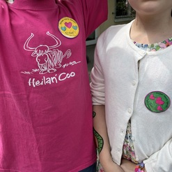 Zwei Kinder mit einem pinken T-Shirt und einem wei&szlig;en Cardigan, jeweils mit bunten Ansteckern.