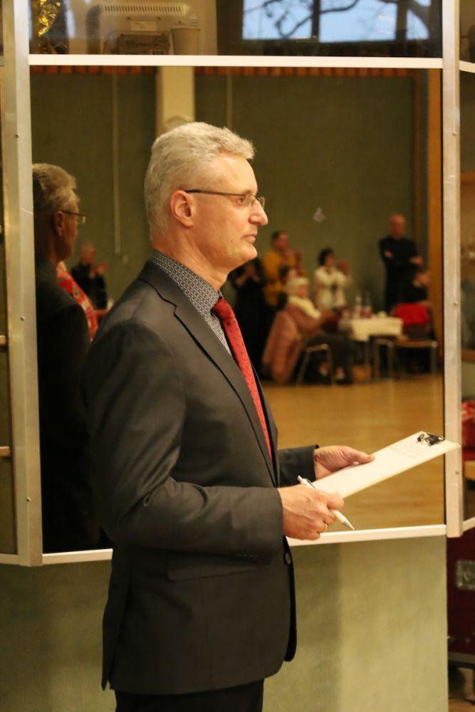 Ein Mann in einem Anzug steht seitlich vor einem Spiegel und h&auml;lt ein Notizblatt mit einem Stift in der Hand.