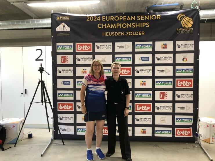 Conny und Jutta bei der EM der Altersklassen in Belgien Zwei Frauen stehen vor einem Banner der 2024 European Senior Championships in Heusden-Zolder.