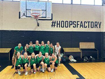 Gruppe von Basketballspielern in grünen Trikots posiert vor einem Basketballkorb in der Halle #HOOPSFACTORY.