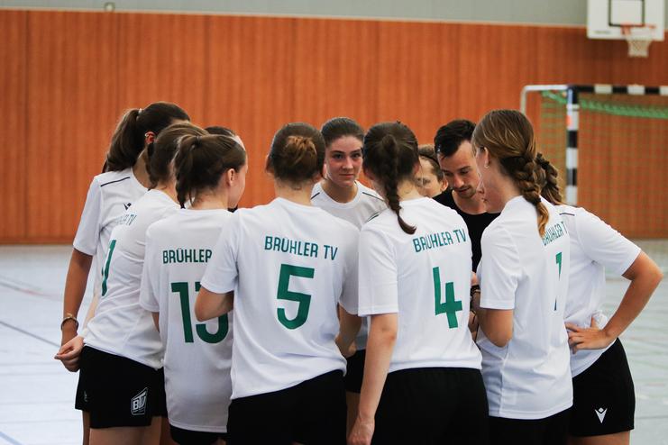 Begegnung einer Handballmannschaft in Trainingskleidung, die sich zur Besprechung versammelt.