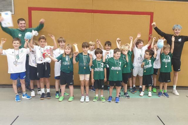 Gruppe von Jugendlichen in Sportkleidung mit Medaillen, die jubeln und feiern in einer Sporthalle.