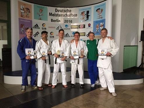 Sechs Judokas in weißen und blauen Gi halten Pokale bei der Deutschen Meisterschaft 2016 in Berlin.
