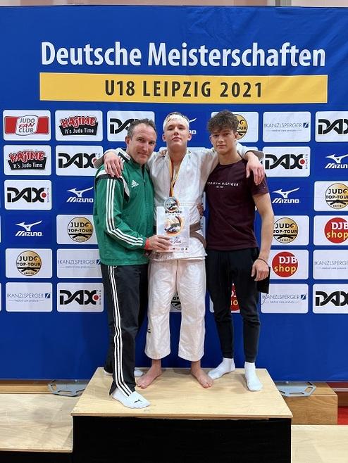 Drei junge Judoka posieren auf einem Treppchen bei den Deutschen Meisterschaften U18 in Leipzig 2021, mit Pokal in der Mitte.