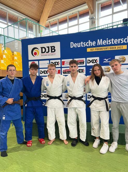 Sechs Judoka in Wettkampfanzügen stehen vor einem Banner der Deutschen Meisterschaft U21 in Frankfurt/Oder.