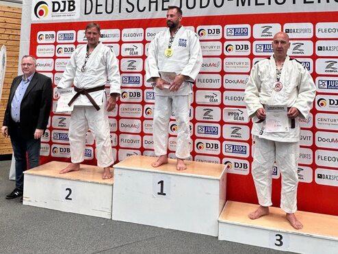 Drei Judoka stehen auf dem Siegerpodest bei den Deutschen Judo-Meisterschaften mit einer Medaille und Urkunde.