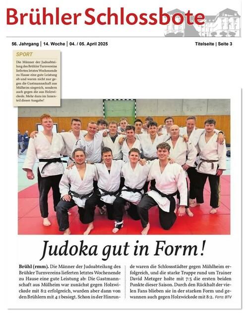 Gruppe von Judokas in Trainingsanzügen posiert auf einer roten Judomatte, lächelnd für ein Gruppenfoto.