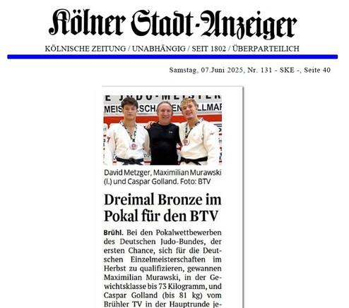 Drei Judoka in Uniform stehen lächelnd zusammen, halten Medaillen, vor einer Judo-Hintergrundwand.