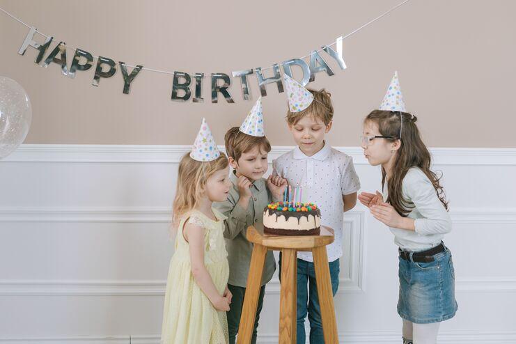 Geburtstagsfeier Group of children celebrating a birthday with cake and decorations indoors.