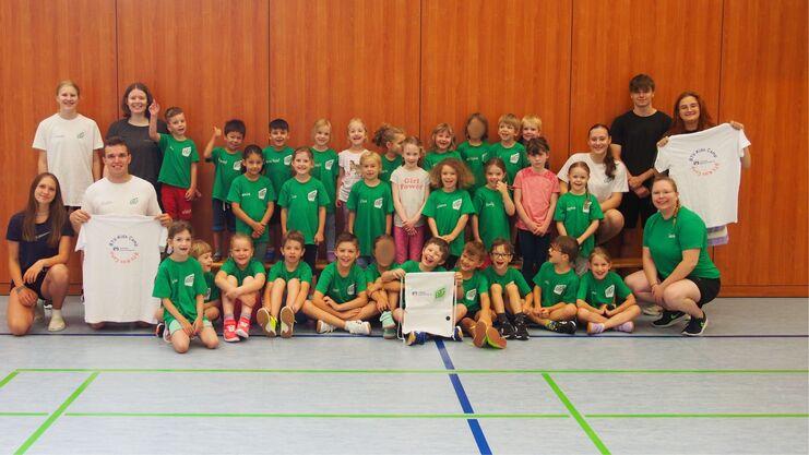 Gruppenfoto des BTV-Kids Camps mit Kindern in gr&uuml;nen T-Shirts und Betreuern auf einem Sporthallenboden.