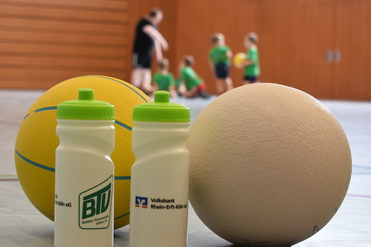 B&auml;lle und Flaschen im Vordergrund zu spielenden Kindern des Kids Camps