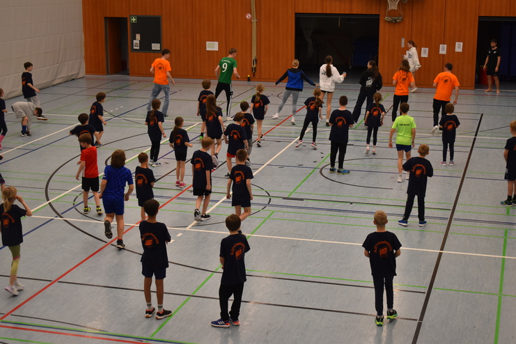 Gruppe von Kindern in Sportkleidung, die in einer Halle ein gemeinsames Training absolvieren.