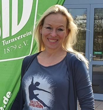 Zwei Personen stehen lächelnd vor einem Eingang, neben einem grünen Banner des Brühler Turnvereins.