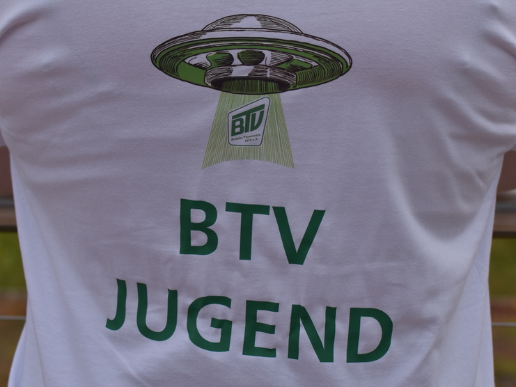 Rückansicht eines T-Shirts mit dem Aufdruck „BTV JUGEND“ und einer UFO-Grafik auf einem weißen Hintergrund.