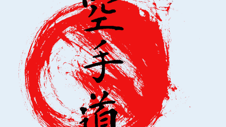 Schwarze Schriftzeichen „Karate“ in japanischer Kalligraphie, umgeben von einem roten Pinselstrich auf hellem Hintergrund.