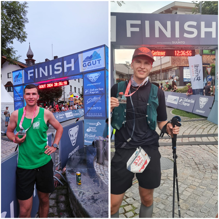 Zwei Läufer stehen am Zielbogen eines Rennens, jeder mit Medaille und unterschiedlichen Outfit.