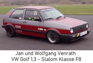 VW Golf 1.3 in rot-grau beim Slalomfahren auf einem Asphaltkurs, Fahrer und Beifahrer im Innenraum sichtbar.