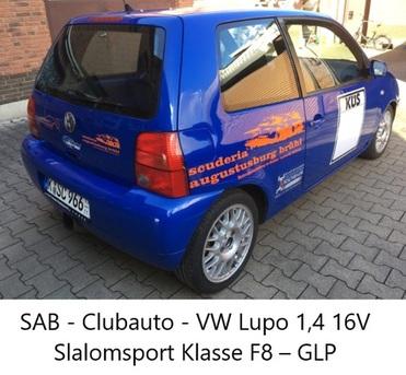 Blauer VW Lupo 1,4 16V mit Aufklebern, geparkt auf einer gepflasterten Fläche. Sicht auf die linke Seite des Fahrzeugs.