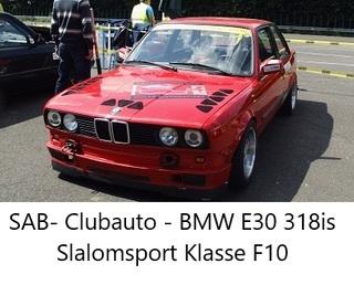 Roter BMW E30 318is mit Sportausstattung auf einem Parkplatz, umgeben von weiteren Fahrzeugen.