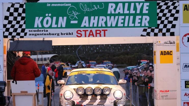 Startlinie der Rallye Köln-Ahrweiler 2019 mit einem Fahrzeug und Zuschauern, im Hintergrund ein beleuchteter Rallye-Bereich.