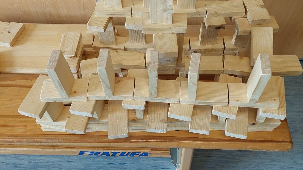 Detailansicht einer Konstruktion aus Holzklötzen auf einem Tisch, umgeben von einem hellen Hintergrund.