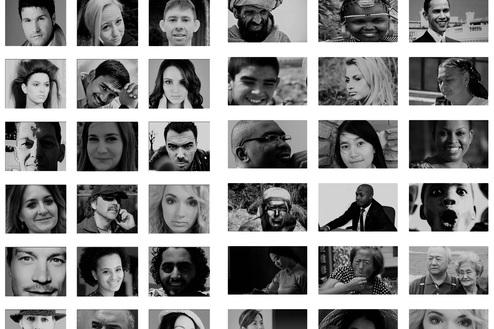 Drei Personen sitzen auf einer Bank und betrachten eine Wand voller Schwarz-Weiß-Porträts.