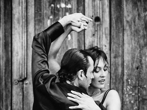 Tanzpaar in einem leidenschaftlichen Tango vor einer rustikalen Holzt&uuml;r, schwarz-wei&szlig; gehalten.