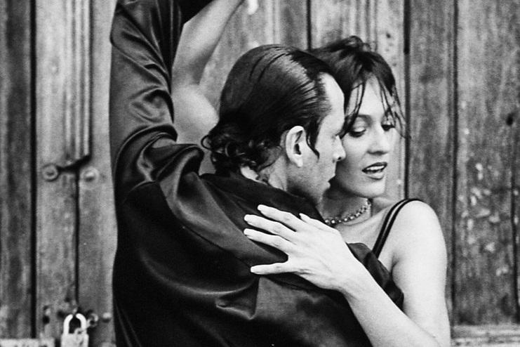 Tanzpaar in einem leidenschaftlichen Tango vor einer rustikalen Holztür, schwarz-weiß gehalten.