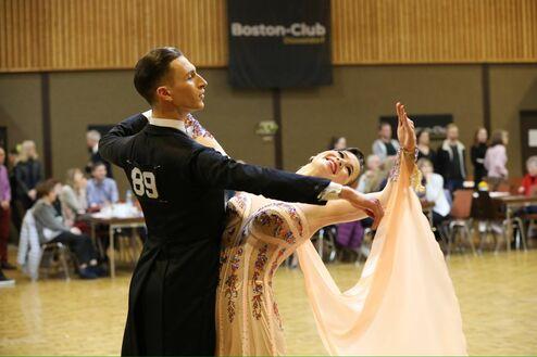 Tanzpaar in eleganter Kleidung bei einer Parkettveranstaltung, der Mann führt die Partnerin in einer dynamischen Pose.