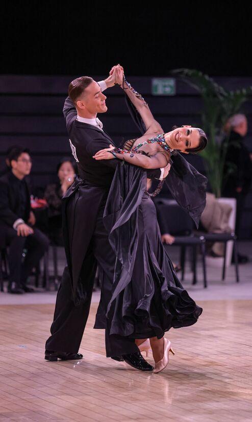 Tanzpaar in eleganter Kleidung führt eine Drehung auf dem Parkett während eines Wettbewerbs.
