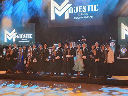 Gruppe von Tänzern in eleganten Outfits beim Majestic Dance Tournament auf einer beleuchteten Bühne.