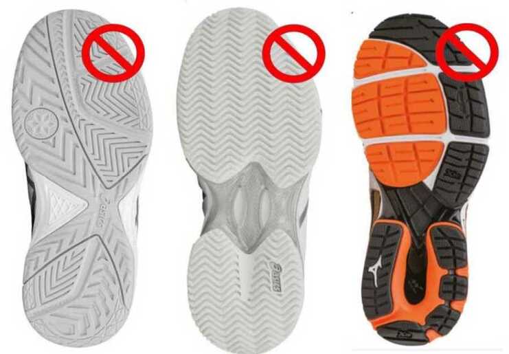 Drei Schuhsohlen mit roten Verbotssymbolen, die auf unerwünschte Merkmale hinweisen.