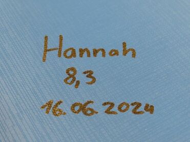 Name "Hannah", Note 8,3 und Datum 16.06.2024 sind in brauner Schrift auf einer blauen Oberfläche geschrieben.