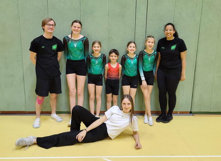 5 Junge Turner stehen mit ihren Trainern, alle gut gelaunt