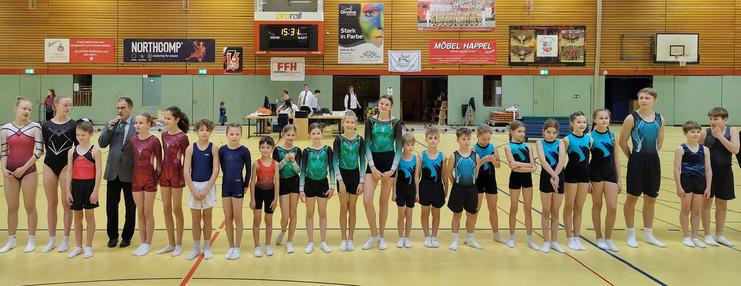 Junge Turner von allen Manschaften stehen in einer Reihe in der Halle