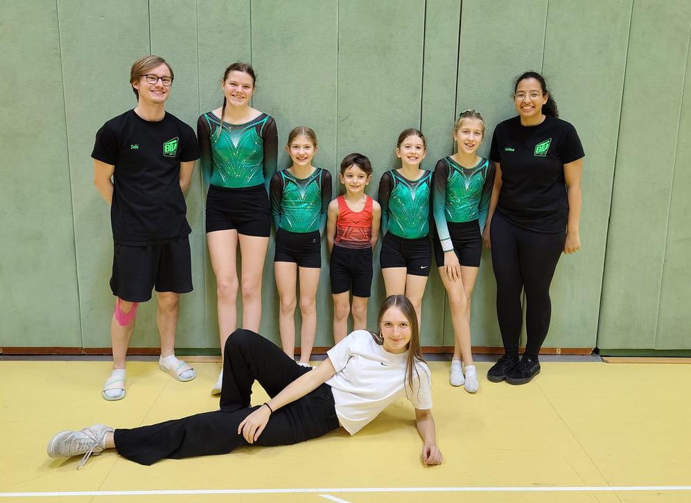 5 Junge Turner stehen mit ihren Trainern, alle gut gelaunt