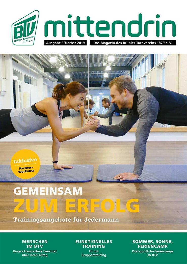 Zwei Personen im Plank halten einen Armwrestling-Wettbewerb auf Yogamatten in einem hellen Fitnessraum.