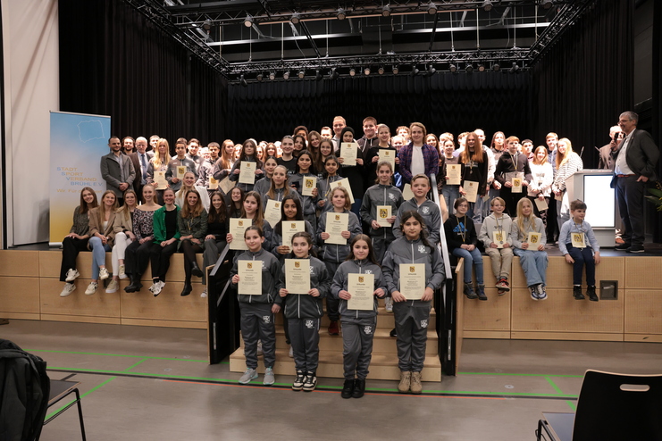 Gruppenfoto von Sportlern mit Urkunden auf einer B&uuml;hne, im Hintergrund eine Banner des Stadt Sport Verbands Bruchsal.